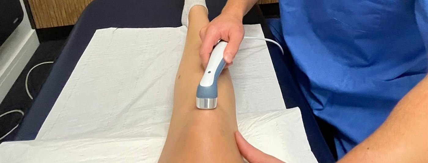 A physiotherapist treating a patient's lower leg with an ultrasound device